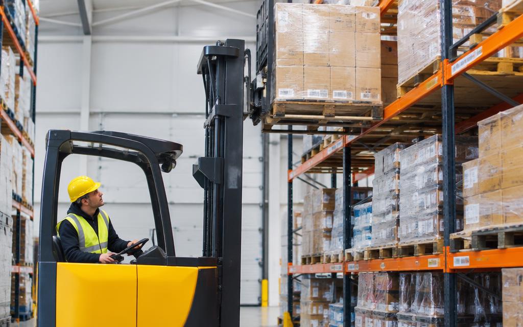 Forklift operator placing a pallet onto high racking