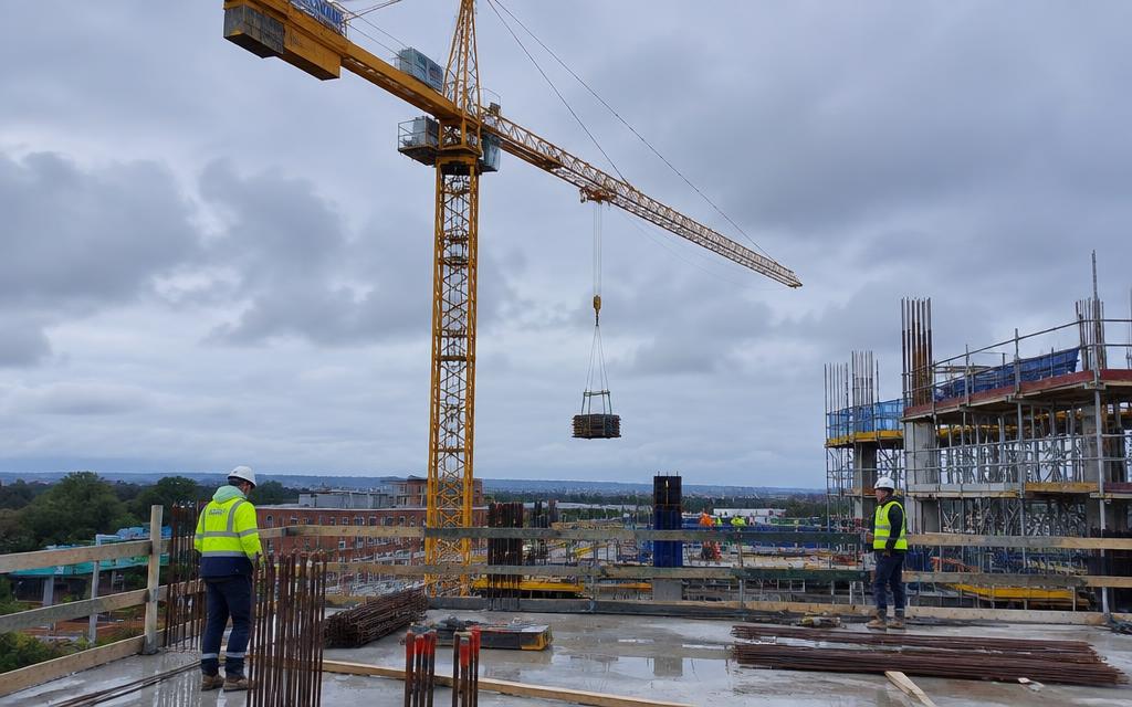 Construction site with tower crane and site workers in hi-vis